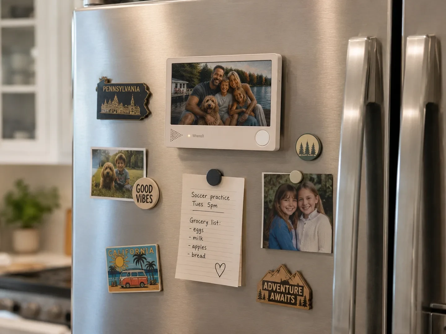 The Wherezit device held by its magnetic back on a stainless steel fridge door, with a handwritten paper note stuck up beside it.