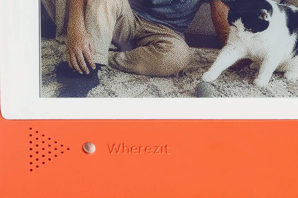 Close-up of the speaker and microphone openings on an orange Wherezit e-paper photo frame.